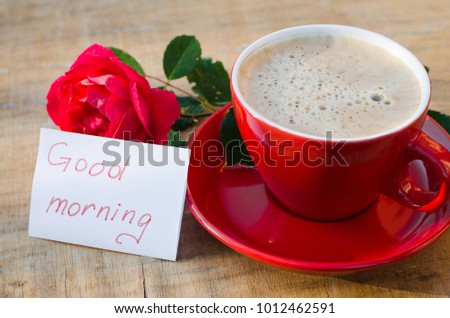 Coffee cup with red rose flower and notes good morning on wooden rustic table from above, breakfast on Mothers day, Womens day or Valentines day