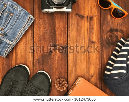 Hat, black sneakers, camera, sunglasses, backpack and diary on wood background.