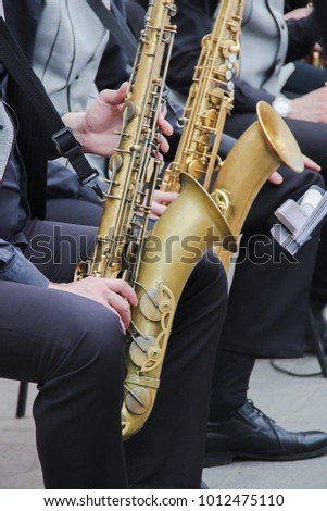 Saxophonists playing in a jazz band, dressed in men's classic vest and trousers. Close up shoot of hands
