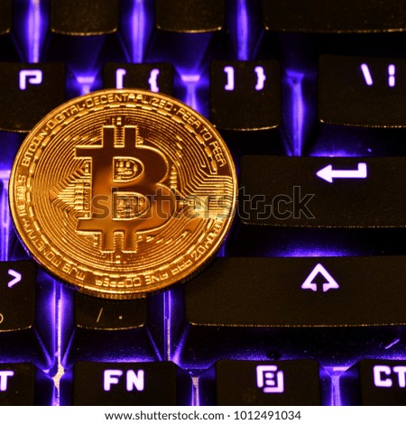 Bitcoin. Crypto currency Bitcoin, BTC, Bit Coin. Macro shot of Bitcoin golden coin on the illuminated keyboard background. Blockchain technology, bitcoin mining concept