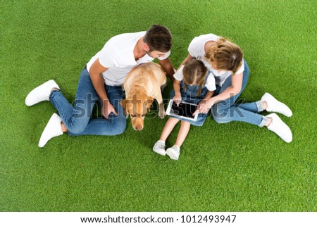 overhead view of family using digital tablet while sitting on green grass