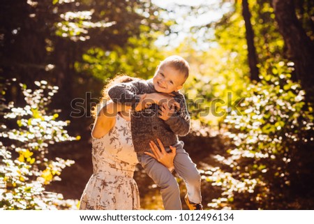 Autumn sun shines around mommy and son posing in the park