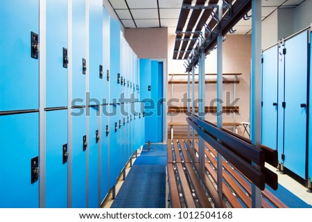 an empty locker room in the sports club, school, section. line lockers with numbers and locks and a shower. in the center a wooden clothes hanger and a dressing-gown Royalty-Free Stock Photo #1012504168