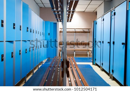 an empty locker room in the sports club, school, section. line lockers with numbers and locks and a shower. in the center a wooden clothes hanger and a dressing-gown Royalty-Free Stock Photo #1012504171