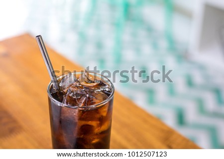 Close up on a tumbler glass full of diet cola and ice, with a reusable metal drinking straw, on a wood restaurant table  Royalty-Free Stock Photo #1012507123