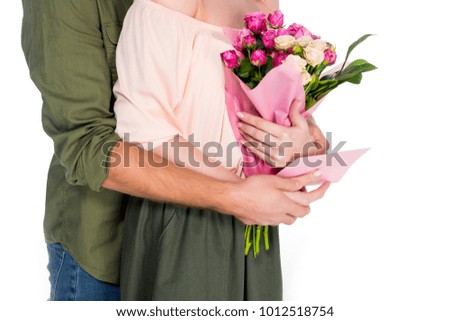 partial view of man hugging wife with bouquet of flowers and postcard isolated on white