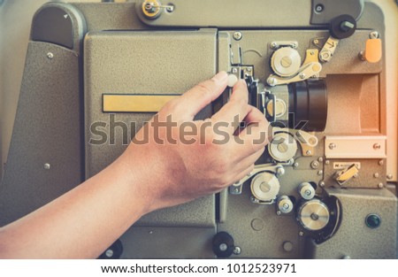 Close up of vintage classic film projector with vintage color style. Old vintage rolling film projector with with man hand for background.