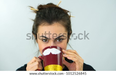 Portrait of a brunette girl holding a funny cup with a white mustache