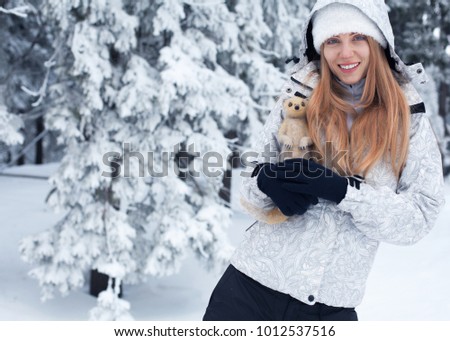 girl on the background of snow and snow-covered pine trees with toy mongoose in hands