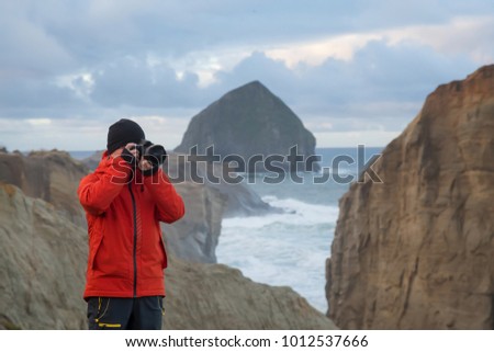 Photographer is taking pictures of the beautiful seaside view on the Oregon Coast. Taken in Cape Kiwanda, Pacific City, during a cloudy winter sunsrise.