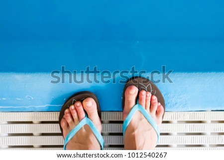 female legs in slippers at the edge of the pool. Water sports as a way to prevent the occurrence of varicose veins. The initial stage of varicose veins. Health Benefits of the pool for Vein Diseases. Royalty-Free Stock Photo #1012540267