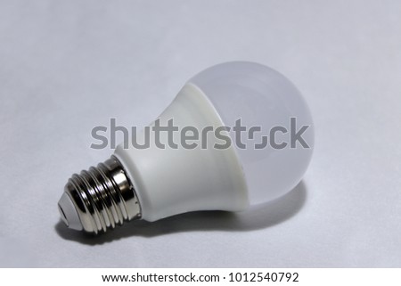 White light bulb on the white background. it is a glass bulb inserted into a lamp or a socket in ceiling, that provides light passing by an electric current through a filament or a pocket of gas inert