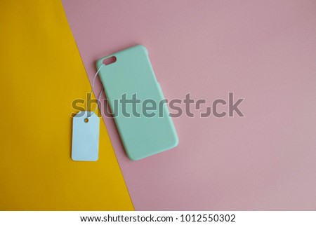 Colorful concept : Top view of mock up clear phone case pastel green with price tag on pink and yellow paper color background, copy space, branding, corporate