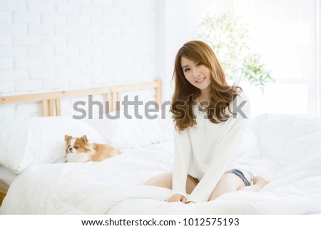 Asia woman looks bright in white bed in bedroom I'm happy with the smile of friendship between the people and the dog. Pet Fashion Photography with Owner, Clean care does not cause wool allergies.
