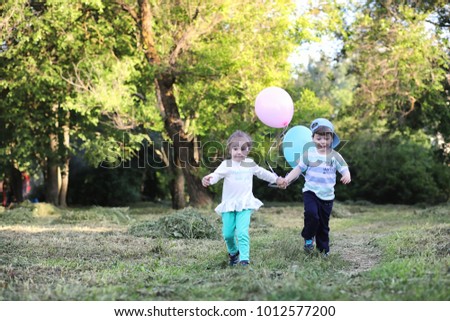 Little children are walking in a park with balloons
