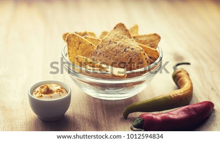 Corn chips in the jar. Traditional snack for beer Mexican nachos. Nachos with spices and pepper on wooden table.