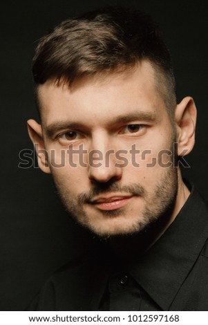 Handsome and positive guy in a black shirt on a black background