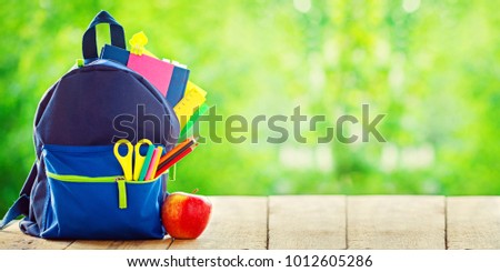 Banner. Full School backpack with apple on wooden and nature green background