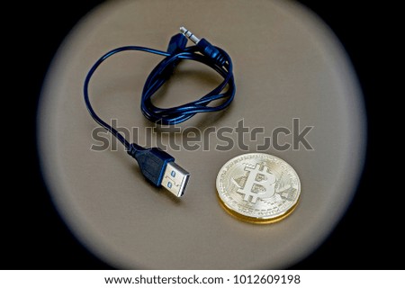 Digital kriptonite bitcoin with a USB cable on a bronze background. Abstraction review element vignetting to give emphasis to the object.