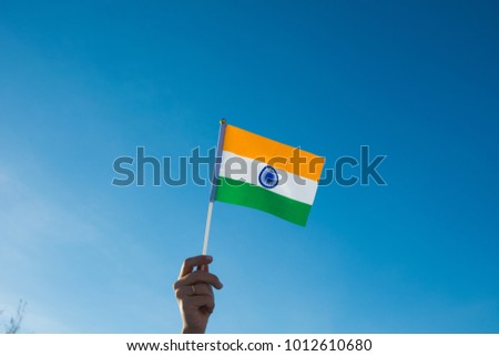 Female hand waving a India flag on a blue sky