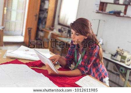 Young fashion designer creating new clothing models, making sketches on her tablet computer
