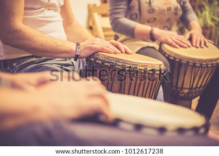 Close up of hands on african drums, drumming for a music therapy (color toned image)