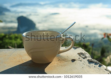 Cup off coffee in the morning with foggy mountain background