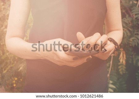 The girl's hand with the black smartphone. Close up.