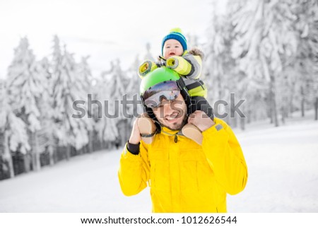 Portrait of a happy father with baby boy standing in winter spots clothes outdoors during the winter vacations