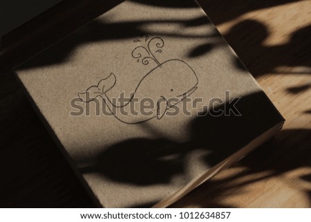 A picture of a whale on a cardboard box covered in shadows
