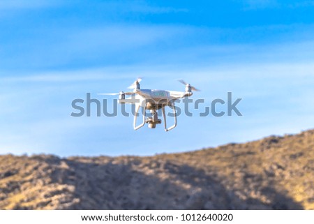 drone quad copter with high resolution digital camera flying hovering in the blue sky.