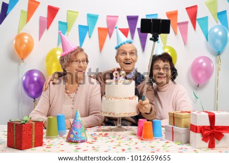 Happy seniors taking a selfie with a stick at a birthday party