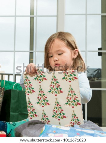 Young female toddler girl at Christmas opening presents and gifts