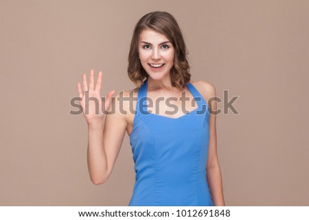 Well hi! Business woman showing hello sign at camera. Studio shot, light brown background