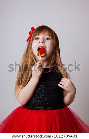 a girl in a smart black and red dress with a lollipop white background