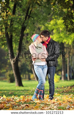 A loving couple kissing in the park in autumn