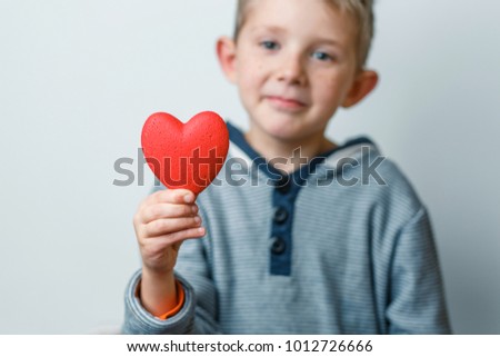 child holds a heart in his hands, a boy with a red heart in his hand, a mother's day, orphans