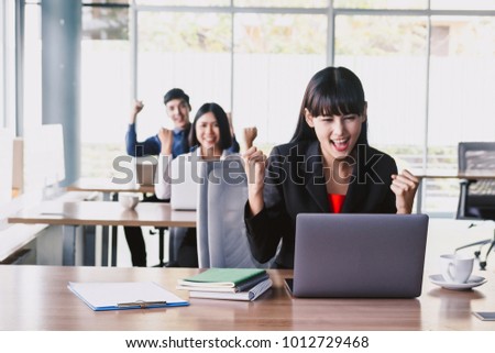 Successful businesswoman celebrating with arms up at office