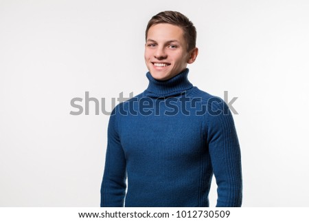 Studio shot of young man wearing blue turtleneck sweater against Royalty-Free Stock Photo #1012730509