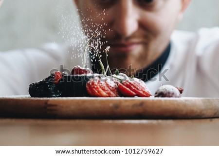 Close up young chef decoration dessert dish in bakery. Royalty-Free Stock Photo #1012759627