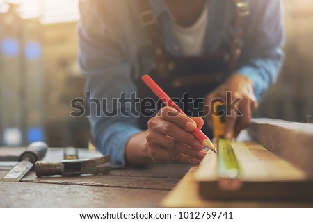Carpenter working on woodworking machines in carpentry shop. A man works in a carpentry shop. Royalty-Free Stock Photo #1012759741