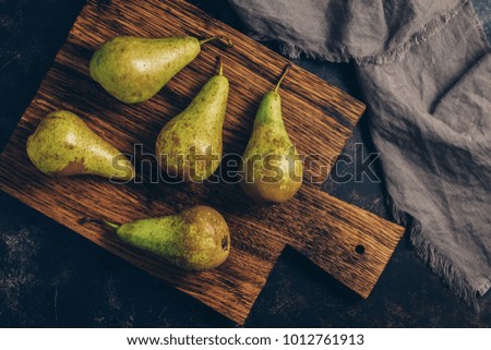 Green pears on an old cutting Board, rustic style toned photo with muted shades