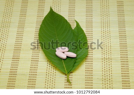 medicine capsule, drug and Mitragyna speciosa leaf (kratom), Kratom is Thai herbal which encourage health on mat