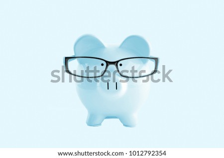 Front view. Blue piggy bank in glasses on pastel blue background