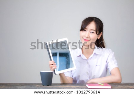 Portrait of thai high school student uniform beautiful girl using her tablet