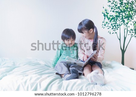 Sister younger brother of Japanese reading a picture book