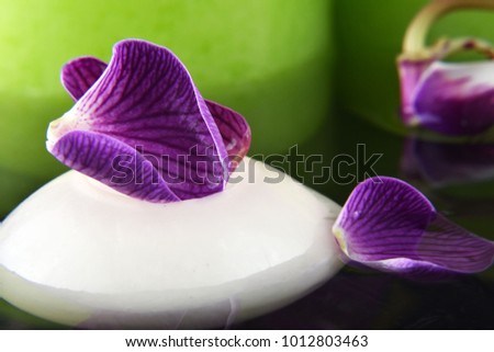 
Beautiful bright tender petals of orchids on water with candles spa concept