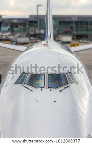 High angle close up of the front windshield and wipers of the jumbo jet nose with the airport as a  background.