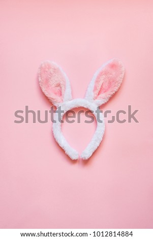 Top view of white fluffy bunny ears over pink background.