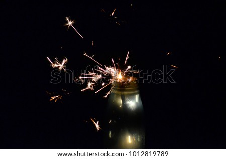 happy holidays.Vintage flim grain Style. Abstract blur background,Glass bottles There are fireworks.holding a burning sparkler light with purple sky background.closeup in female hand in dark.